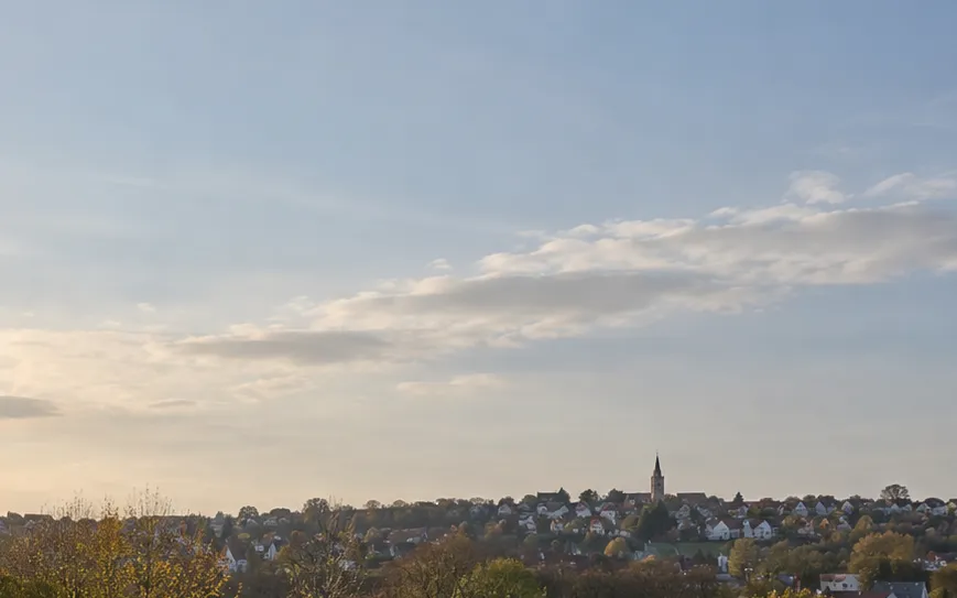Ruhige helle Himmelsfläche über einem Siedlungsrand.